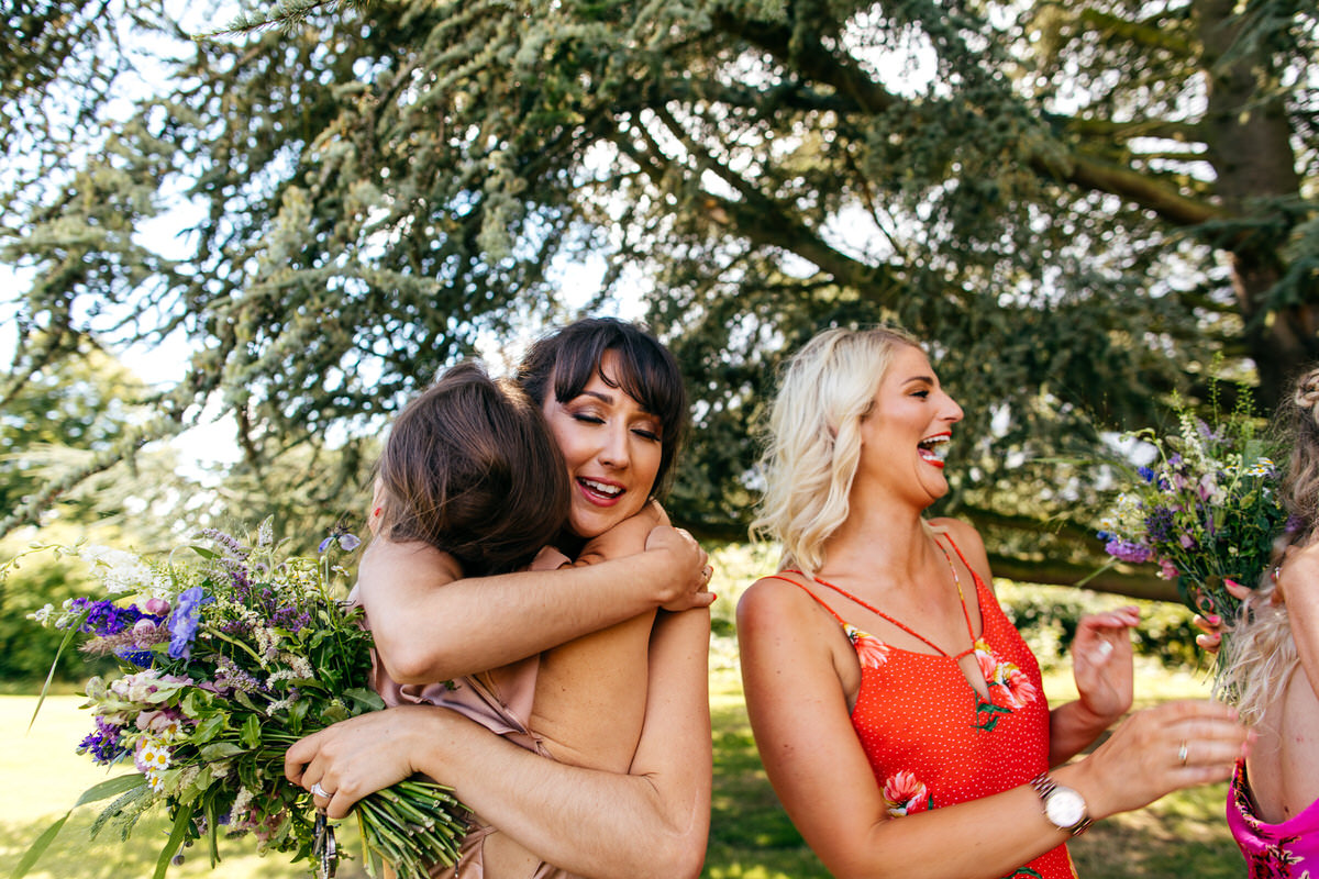 heartfelt hug between bride and her friends at summer wedding Barton Hall