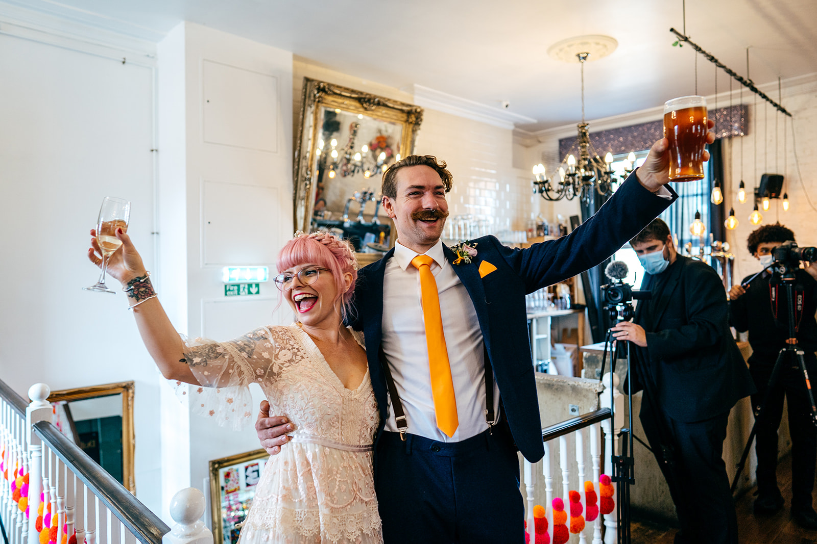 Couple arrive for their wedding breakfast arms in the air 