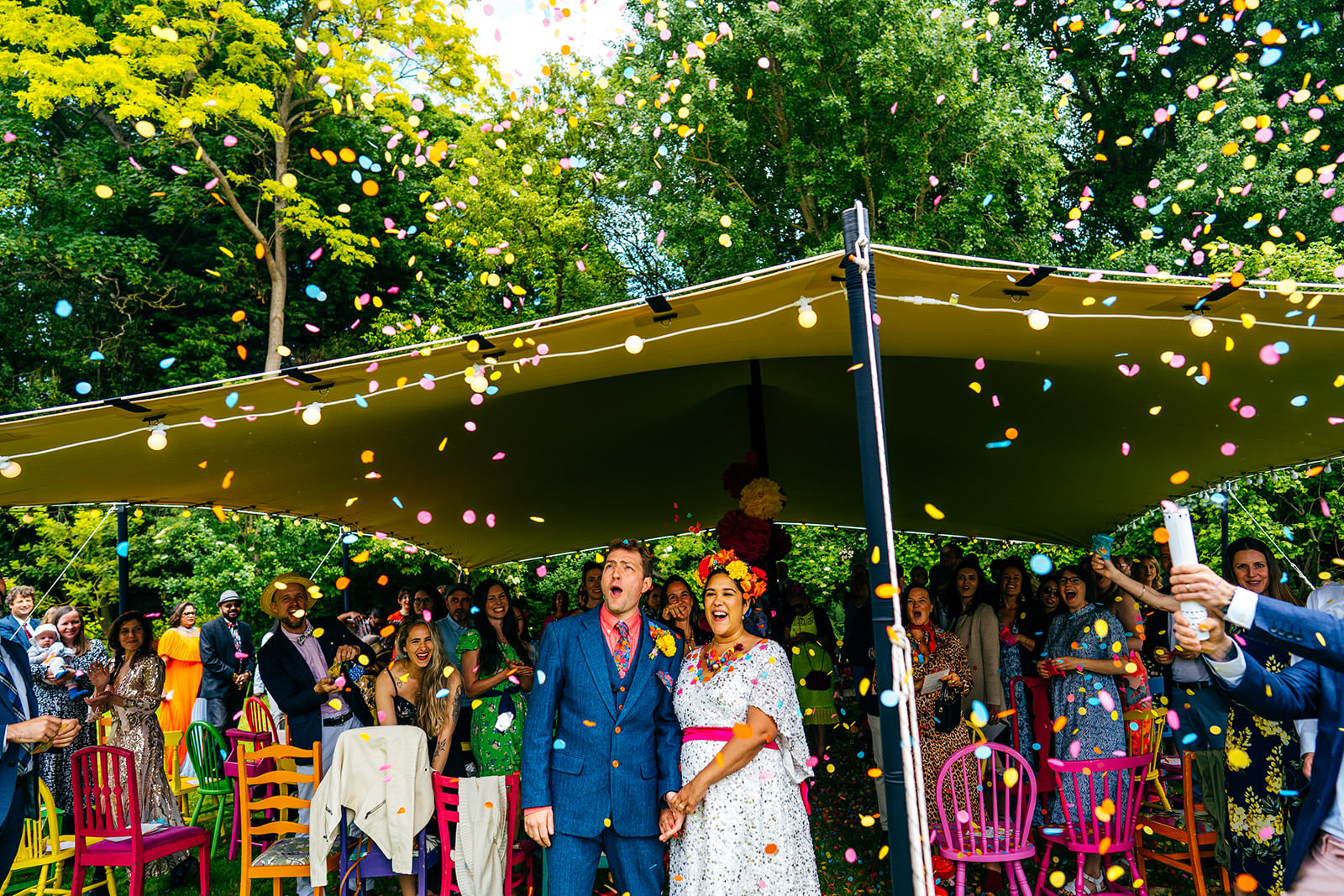 Bride and Groom emerge from canopy to confetti cannon welcome from guests 