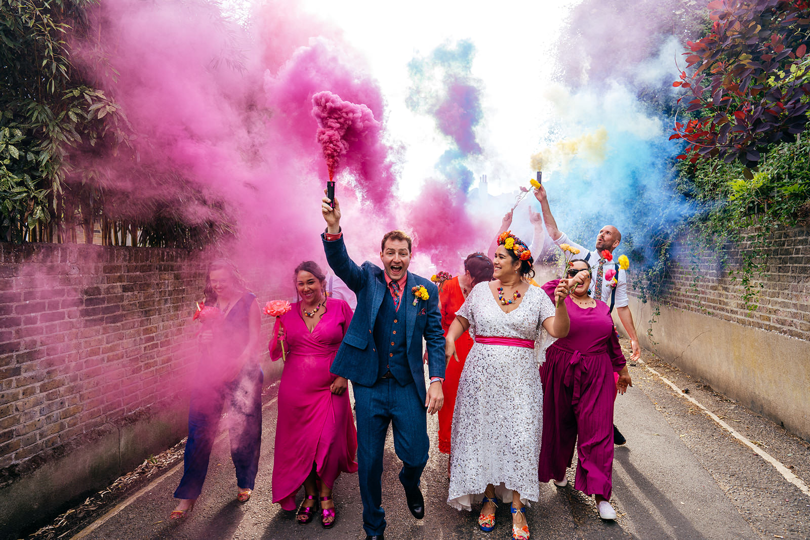 Bridal party walk down London Street with colourful smoke bombs during Secret River Garden Wedding in Twickenham