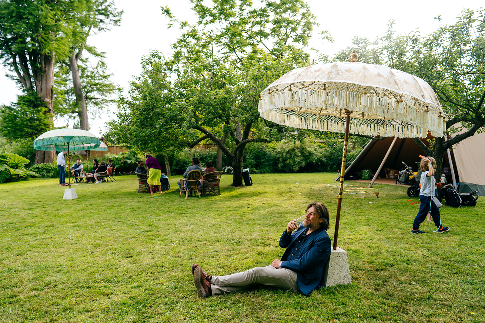 Guest chills under parasol on the lawn of Secret River Garden in Twickenham 