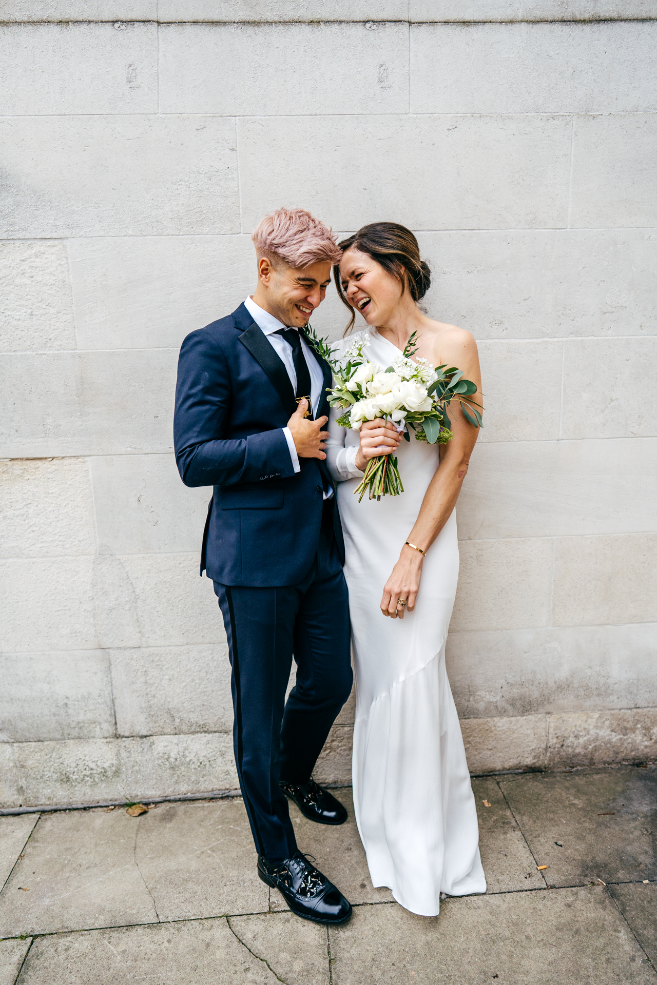 Bride and Groom portrait in Islington. Bride wearing asymetric dress by Rebecca Vallance and Groom wears Hugo Boss suit and his signature pink hair