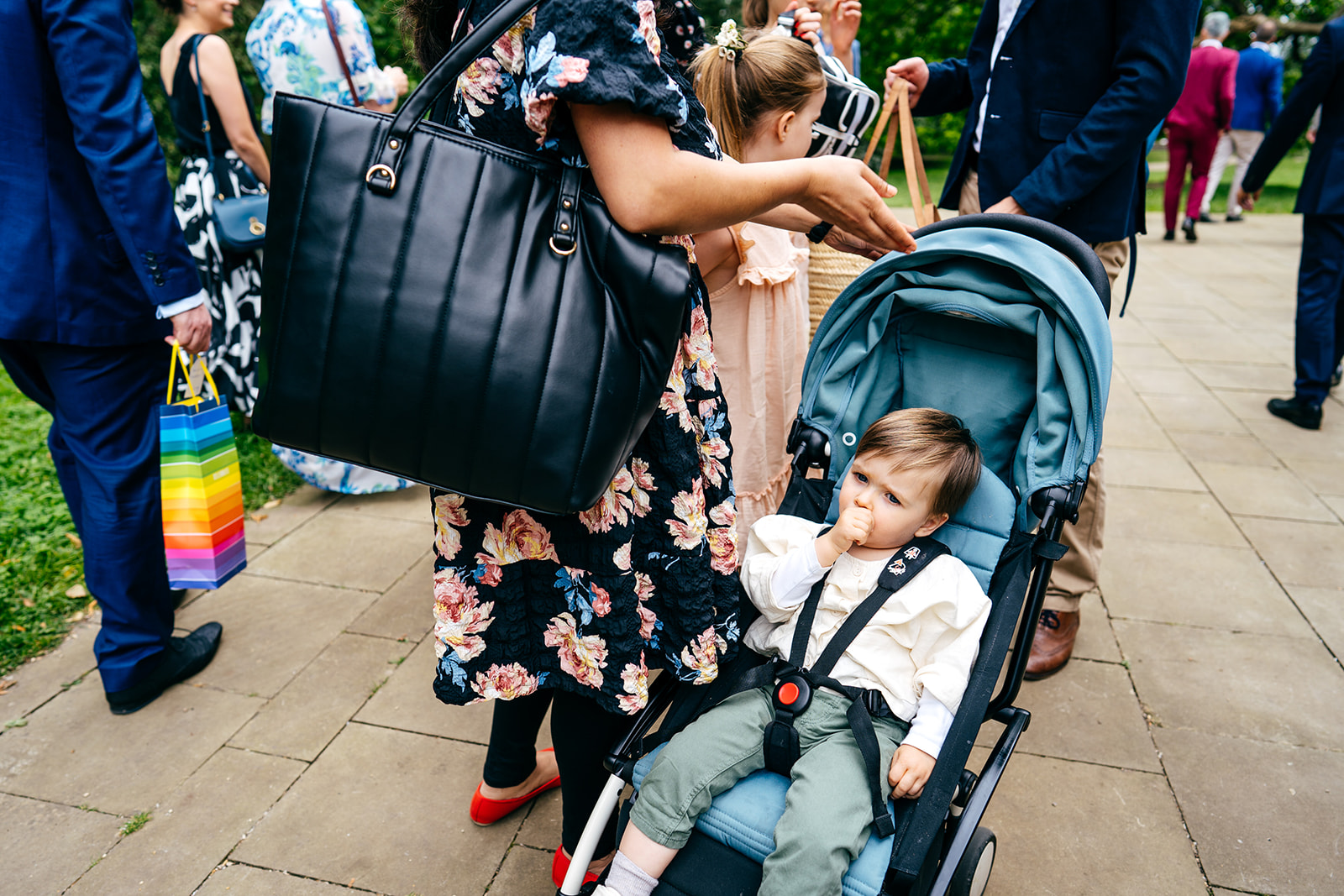 Guests arrive for Twickenham Wedding - baby boy sucking his thumb in pushchair 