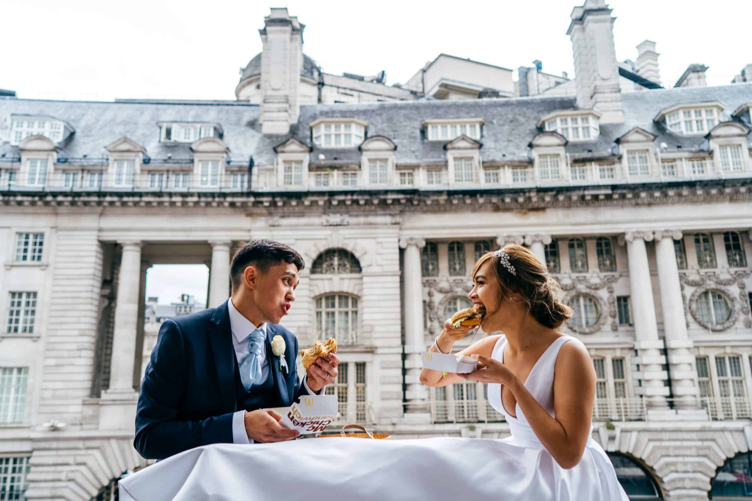 Bride and Groom share a McDonalds on the balcony of Café Royal Wedding photos of the couple.